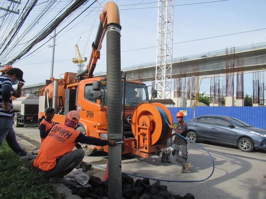 Crew vacuuming a manhole with a boom truck